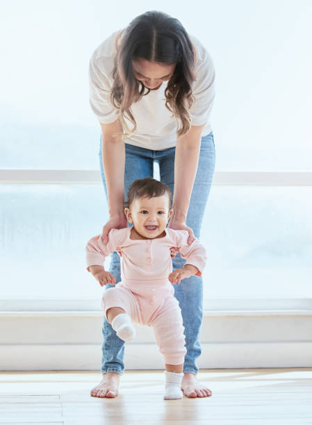 foto de una dulce niña que se une a ella mientras aprende a dar sus primeros pasos en casa - togetherness learning playful mother fotografías e imágenes de stock