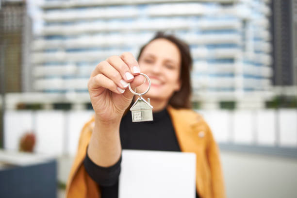 Blurred portrait of young female Real Estate Agent holding key in hand stock photo