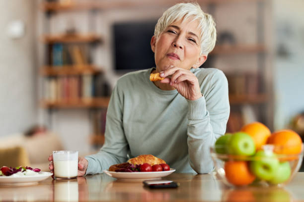 Smiling senior woman eating breakfast at home.
