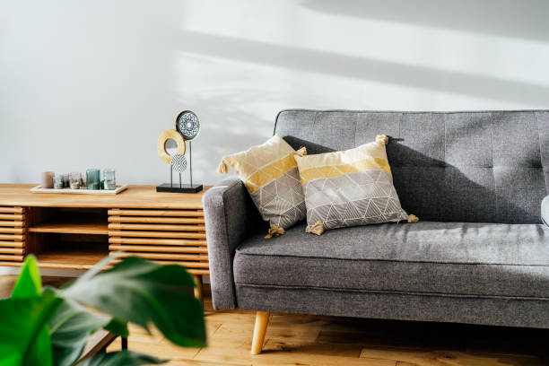 istock Stylish living room interior with designer console with decor and gray sofa with graphic pillows. White walls, green plants in the pots. Light wooden oak parquet. Modern Scandinavian style interior. 1397873977