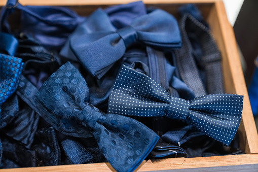 High angle close-up of blue bow ties in wooden container at menswear boutique