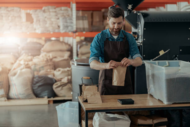 istock Uniformed worker packs roasted coffee beans into packages for sale 1397877503