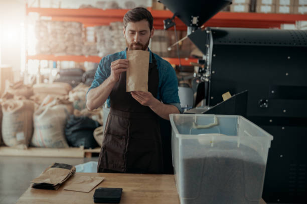 męski barista w mundurze wdychając aromat kawy we własnej produkcji palonych ziaren kawy - coffee contemporary arabica scented zdjęcia i obrazy z banku zdjęć