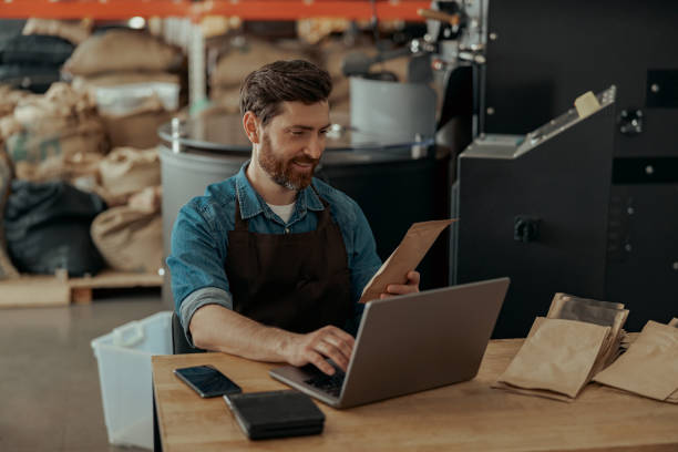Business owner of small coffee roasting factory working laptop on his workplace stock photo
