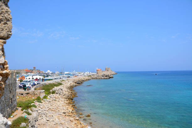 Low angle view of medieval stone towers in Rhodes Old Town, Greece, under a clear blue sky. Historic fortification walls showcasing ancient architecture, cultural heritage, and travel destination concept. No people.