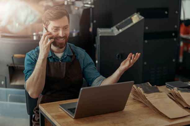 Business owner of small coffee roasting factory talking phone on his workplace stock photo