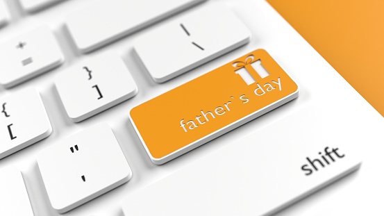 Father's Day gift box icon and text on a orange button of a computer keyboard. Horizontal composition with selective focus and copy space. High angle view. Father's Day concept. Easy to crop for all your social media and print sizes.