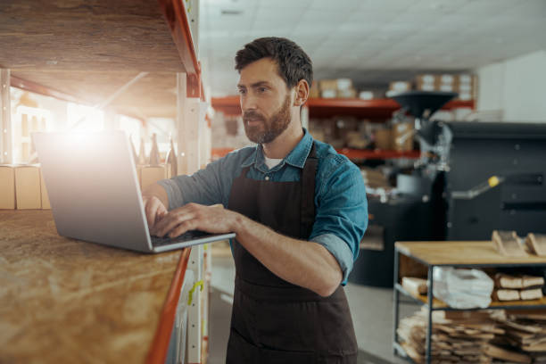 istock Warehouse worker in uniform standing on coffee small factory with laptop 1397879470