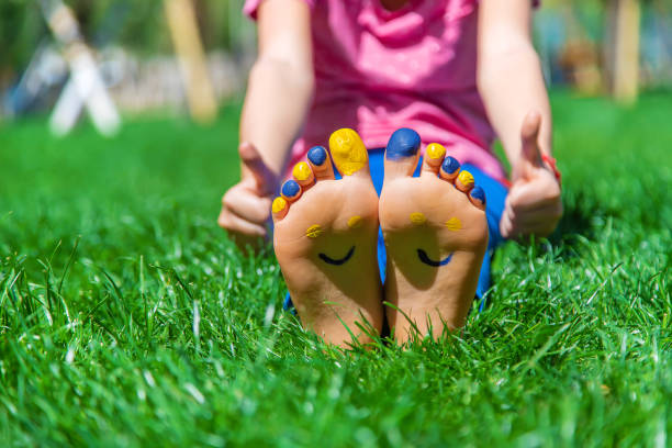 Child feet on the grass Ukrainian flag. Selective focus. Nature.
