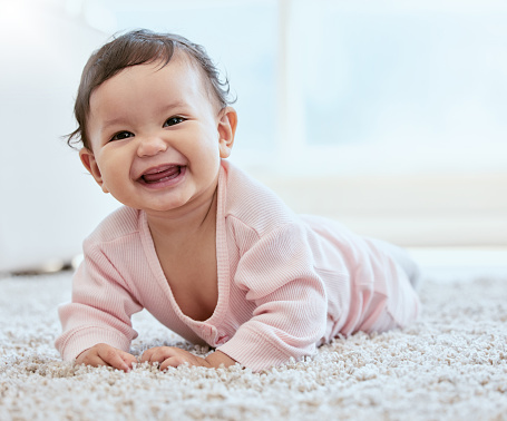 Shot of an adorable baby girl crawling on the floor at home