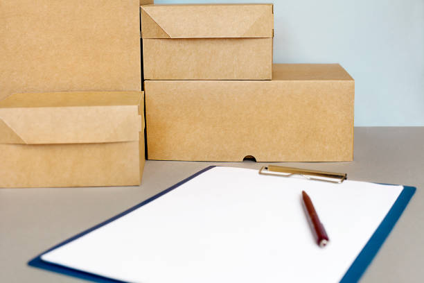стопка картонных коробок и планшет с белым листом лежат на столе - envelope opening stack open стоковые фото и изображения
