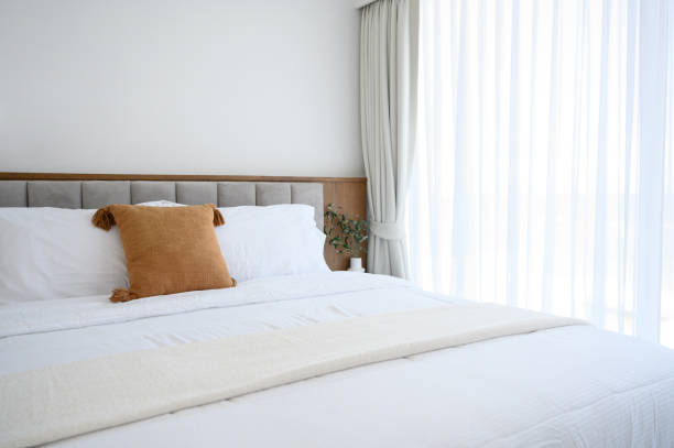 istock Modern interior cozy bed near a window with white curtains in bedroom. pillows and white soft blanket for rest and sleep. 1397881000