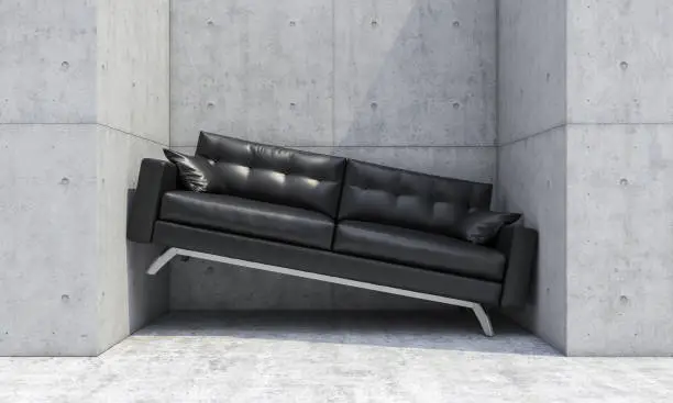 Photo of black sofa wedged between two concrete walls.