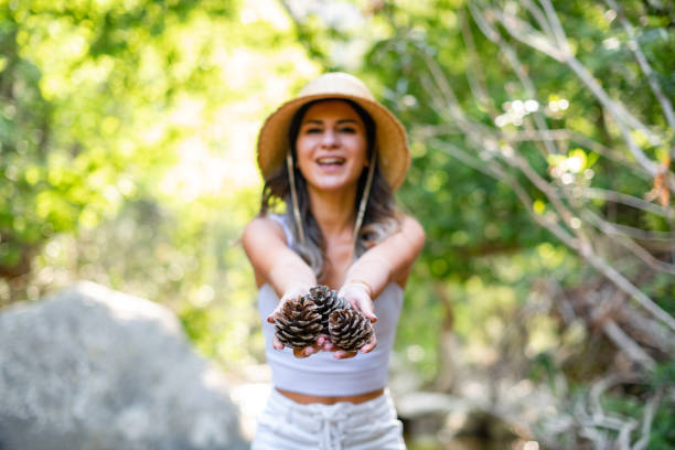 Young Woman Collecting Pinecones in the Forest