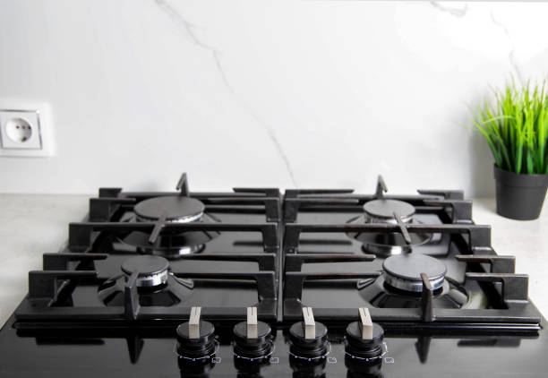 istock Modern kitchen with gas hob against white granite tiles. Decoration pots with artificial flowers. Copy space for text 1397882297