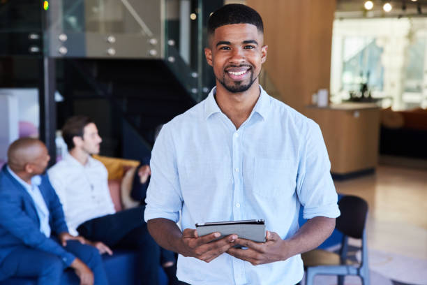 istock Smiling young businessman standing in an office lobby with a digital tablet 1397883721