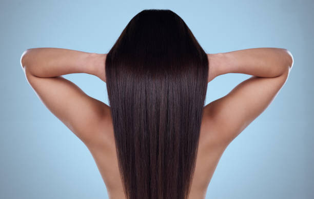 zdjęcie z lotu ptaka z tyłu przedstawiające nierozpoznawalną kobietę z pięknymi jedwabistymi włosami pozującą na niebieskim tle - women long hair rear view beauty zdjęcia i obrazy z banku zdjęć