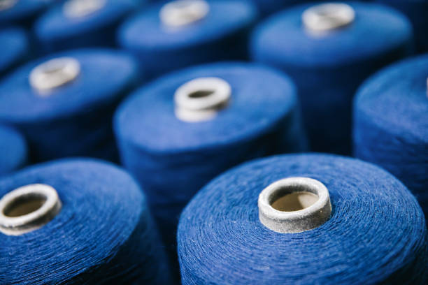 filati o fili di cotone blu su bobine di tubi a bobina presso la fabbrica di filati di cotone. - industria tessile foto e immagini stock