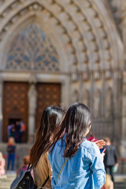 Barcelona, Spain - April 8, 2022: two asian girls in front of the Cathedral of Barcelona (Spain), travel concept.