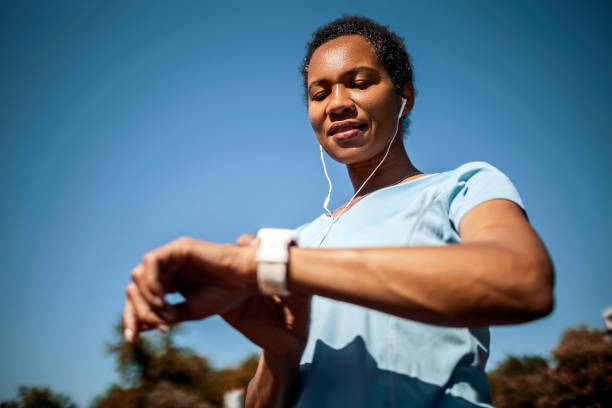 mujer sonriente que controla la frecuencia cardíaca después del entrenamiento deportivo - ordenador para utilizar como accesorio fotografías e imágenes de stock