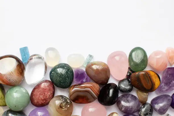 Gems of various colors. Amethyst, rose quartz, agate, apatite, aventurine, olivine, turquoise, aquamarine, rock crystal on white background. Copy space