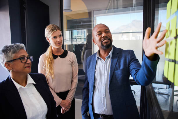 istock Three diverse businesspeople brainstorming with adhesive notes in an office 1397888929