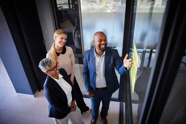 istock Diverse businesspeople laughing during a brainstorming session with adhesive notes in an office 1397888948
