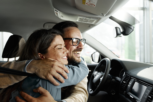 Happy couple enjoying in their hug during road trip in a car.