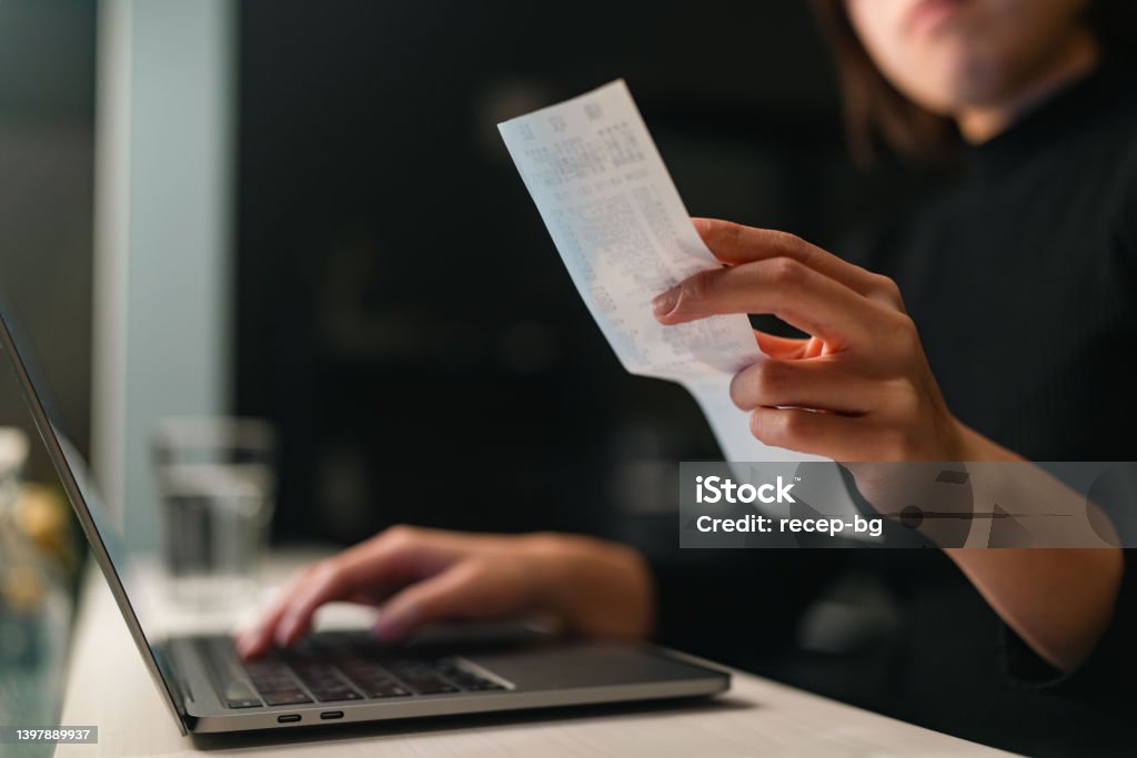 Close-up photo of woman`s hands doing financial planning and checking receipts at home A close-up photo of a woman`s hands doing financial planning and checking receipts at home. Receipt Stock Photo
