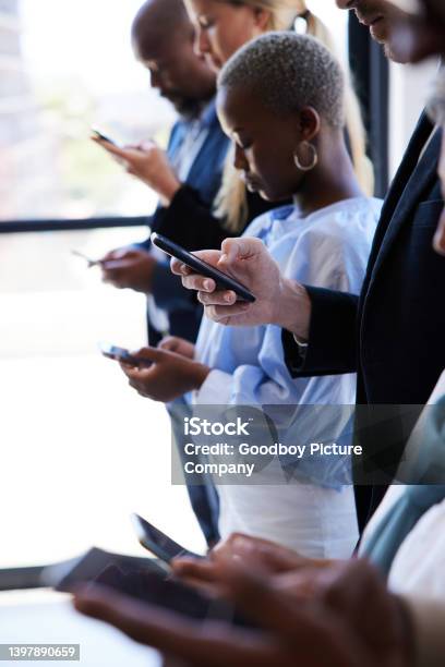 Distracted Businesspeople Using Smart Phones While Standing In An Offfce Stock Photo - Download Image Now