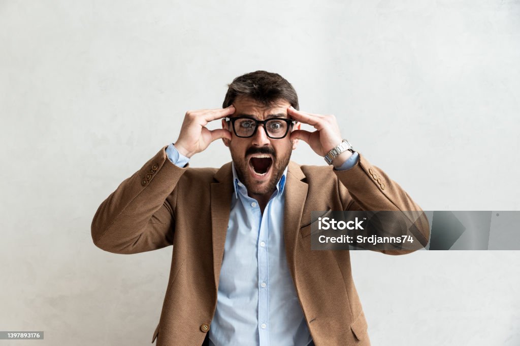 Young office worker mad by stress screaming. Frustrated business man yelling from anger and frustration after he got fired and lost his job. Unemployment concept Anger Stock Photo