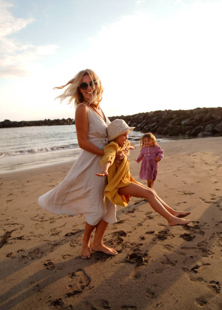istock Joyful mother with two daughters playing on the beach, having fun during sunset, relaxing. Summer vacations with children. Concept of friendly family time on holidays. 1397894776