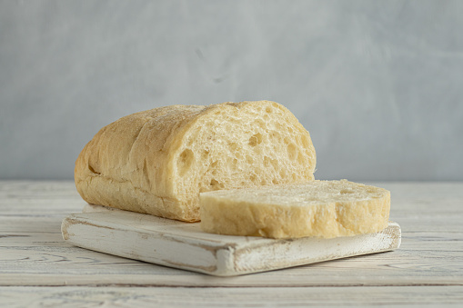 Cutaway ciabatta on the white wooden board. Piece of bread. Loaf of talian bread