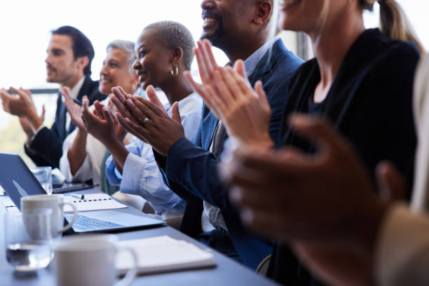 istock Diverse businesspeople smiling and clapping while sitting together at a boardroom table 1397896750