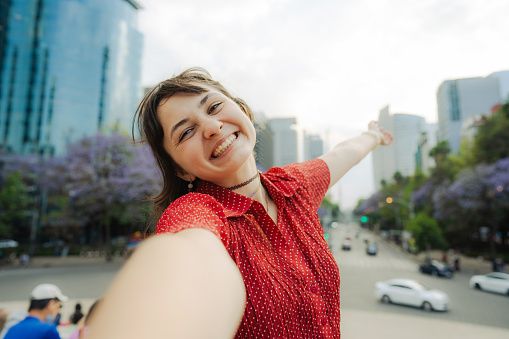Young Caucasian woman in red shirt  making selfie on the background of Mexico cityscape