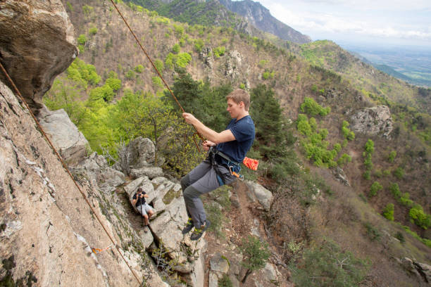 High angle view of young man climbing vertical rock face