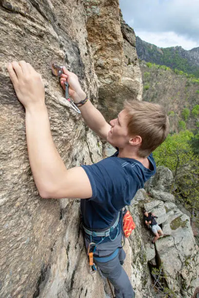 Photo of High angle view of young man climbing vertical rock face