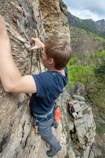 High angle view of young man climbing vertical rock face