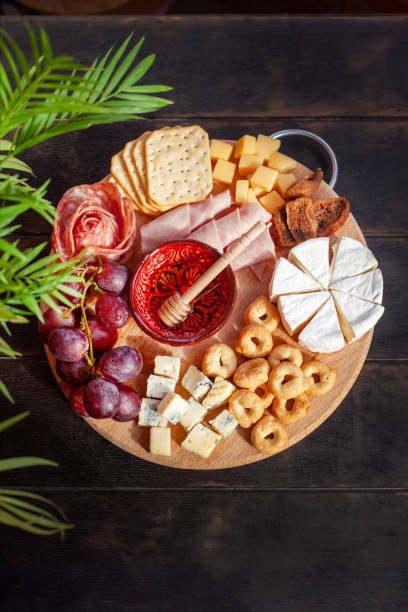 istock Round cutting board with slicing assorted cheese, sausage rosette, ham, cracker, grapes and figs with honey 1397898320
