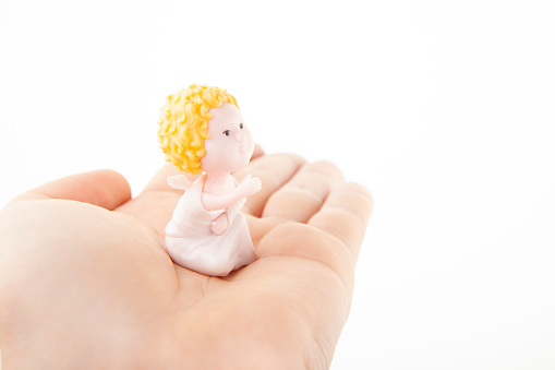 image of miniature angel figure hand white background studio