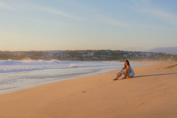 istock Woman sitting on the beach at sunset 1397899803