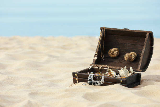 istock Open wooden chest with treasures on sandy beach, space for text 1397902077