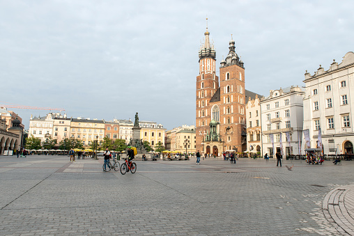 Two bike courriers walk across the Main Square in Cracow, Poland