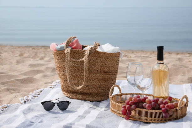 istock Bag, blanket, wine and other stuff for beach picnic on sandy seashore 1397902176