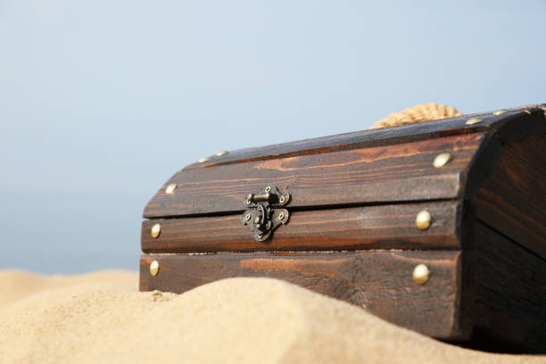 istock Closed wooden treasure chest on sandy beach, closeup 1397902178
