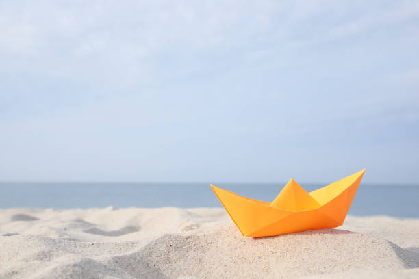 istock Orange paper boat on sandy beach near sea, space for text 1397902593