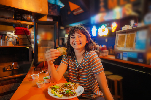 Young Caucasian woman eating taco in a bar