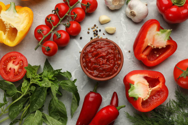 istock Delicious adjika sauce in bowl and ingredients on light marble table, flat lay 1397903407