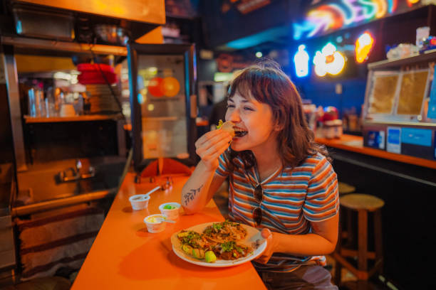 mujer comiendo taco en un bar - taco alimento fotografías e imágenes de stock