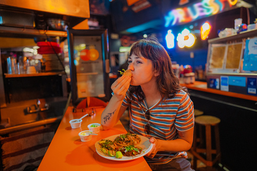 Young Caucasian woman eating taco in a bar